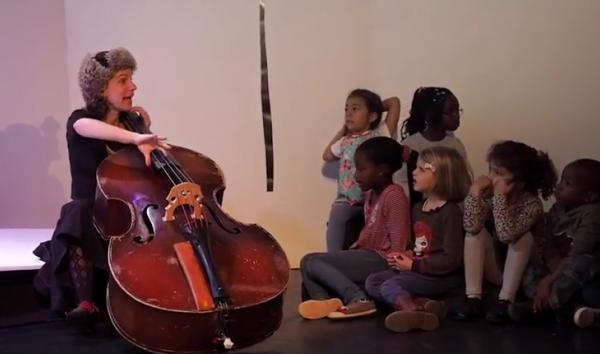 enfants écoutant une artiste jouant du violoncelle